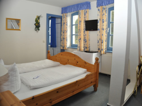Geschmackvolle Kiefermöbel im Doppelzimmer mit blauen Akzenten