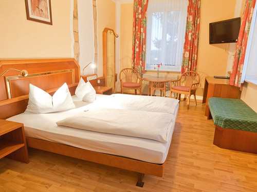 Komfort Zimmer mit Doppelbett, Stühlen, Tisch, TV und Schreibtisch