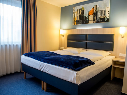 einfaches Doppelzimmer mit Doppelbett und Leselampen
