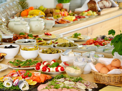 Reichhaltiges Frühstücksbuffet mit verschiedenen Speisen, einschließlich Obst, Käse, Aufschnitt und Eiern.