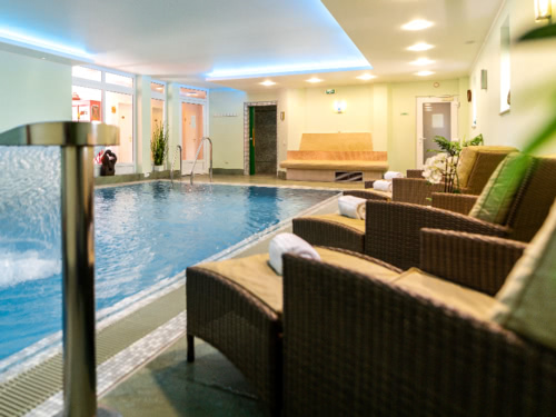 Indoor-Pool mit Wasserfall und Relaxliegen