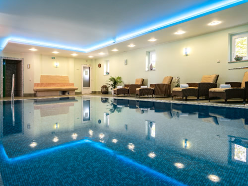Schwimmbad im Badehaus mit Relaxliegen am Rande