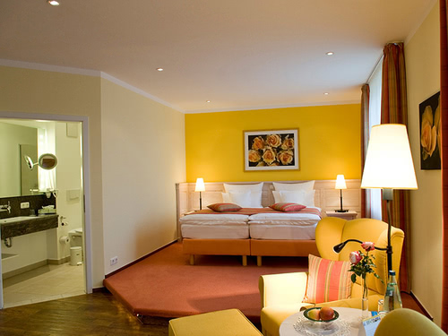 großes Doppelzimmer mit Boxspringbett, Sessel, Tisch und Stehlampe
