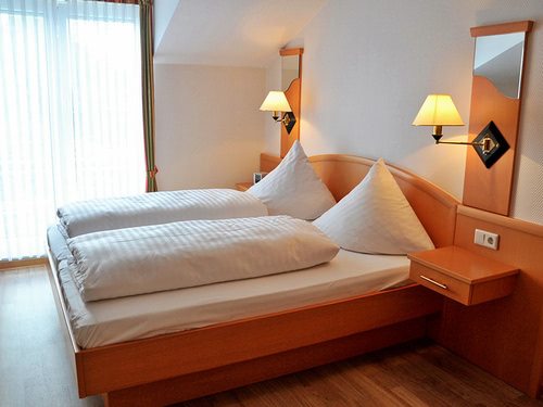 einfaches Zimmer mit Doppelbett und Nachttisch