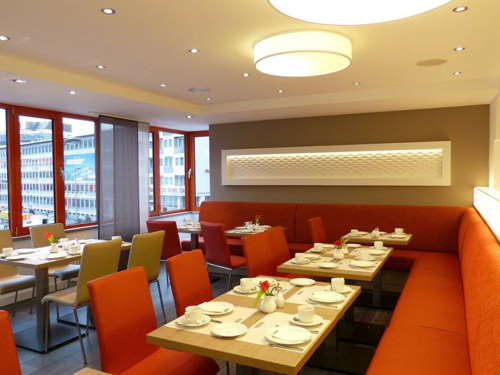 Restaurant mit vielen gedeckten Tischen mit roten Akzenten
