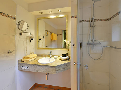 Badbereich mit Dusche, Waschtisch und Wandspiegel