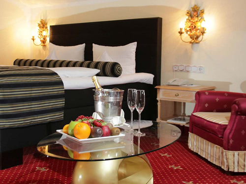 modernes Doppelzimmer mit Sessel sowie Obst und Sekt auf dem Tisch