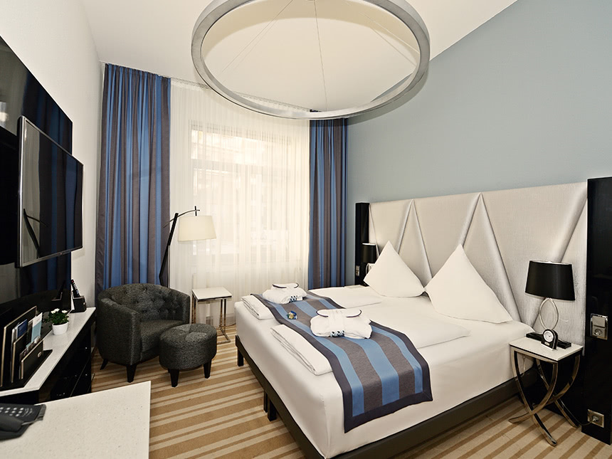 modernes Doppelzimmer mit Boxspringbett, TV, Sessel, Stehlampe und Beistelltisch
