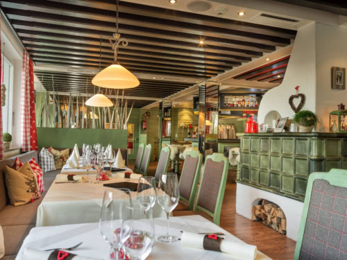 Restaurant mit Kachelofen und eingedeckten Tischen