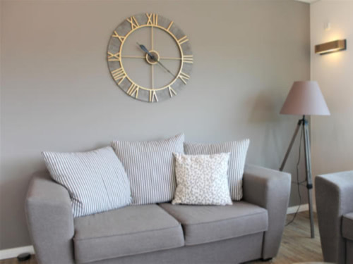 Modernes Wohnzimmer mit grauer Couch und großer stilvoller Uhr